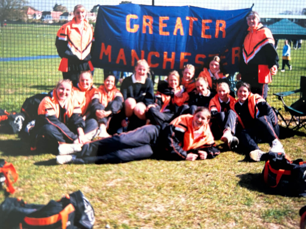 Netball squad holding a Greater Manchester banner.